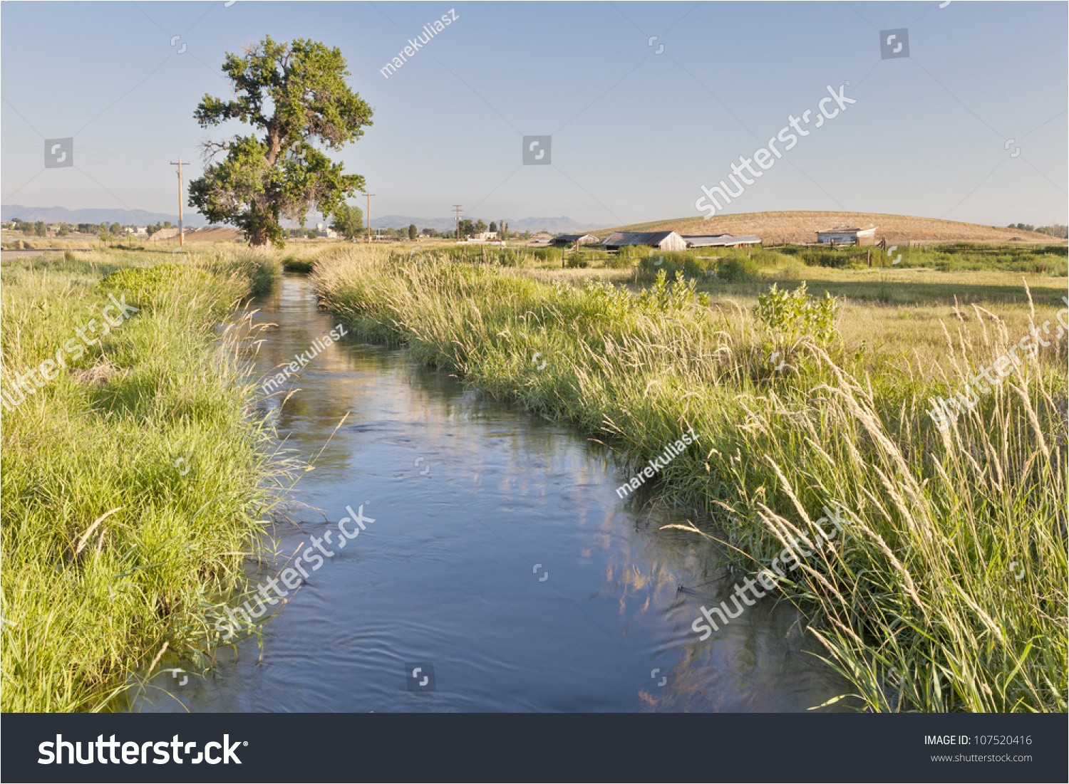 irrigation ditch in colorado farmland near fort collins with rocky mountains at a horizon summer