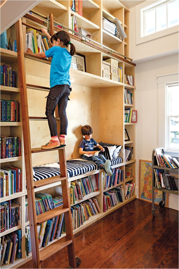 a former closet was transformed into a double height library complete with a reading nook and a rolling ladder perfect for children who love to read