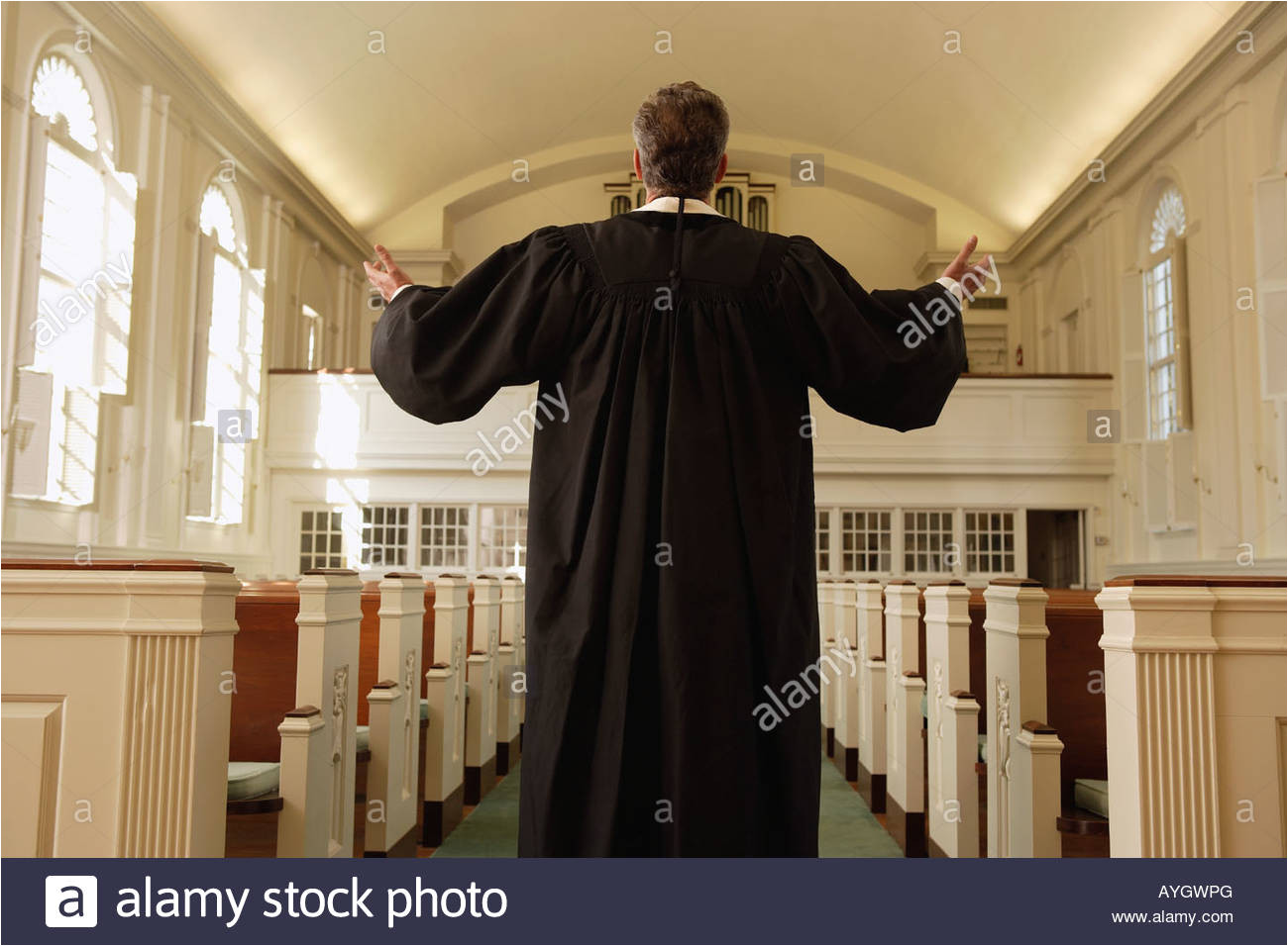 priest with arms raised in church stock image