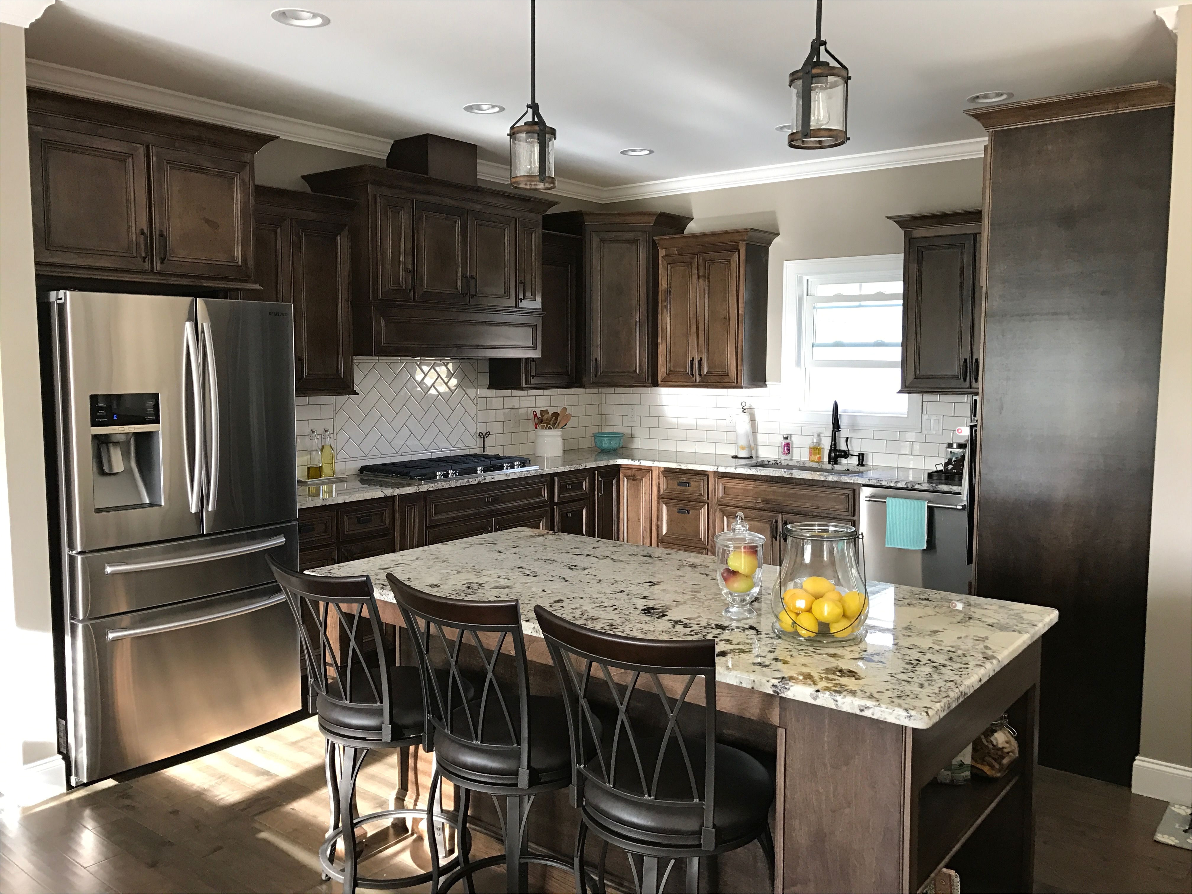 dark walnut stained cabinets alaska white granite white subway tile backsplash with hot cocoa