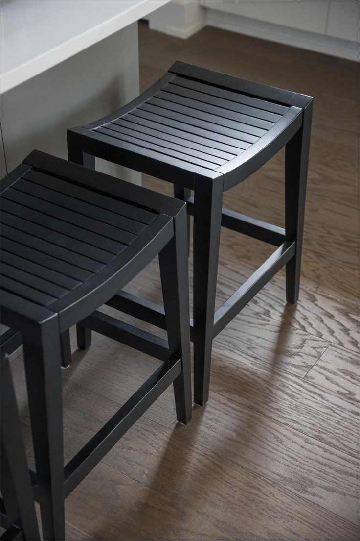 a trio of dark wooden bar stools supplies a comfortable place to enjoy an informal meal at the island table