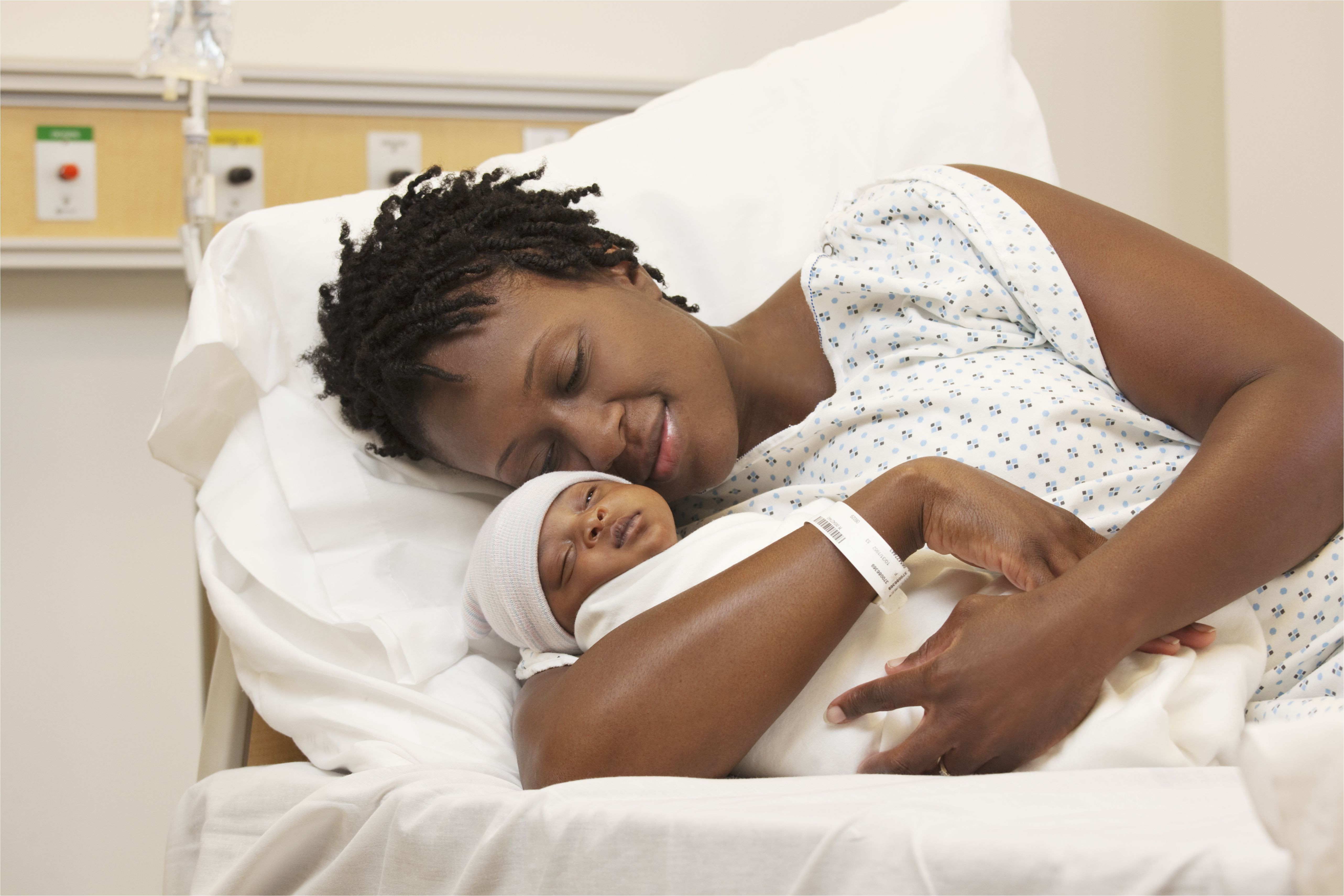 black woman holding newborn baby in hospital bed 140880501 5c1bd3094cedfd00016d52c6 jpg