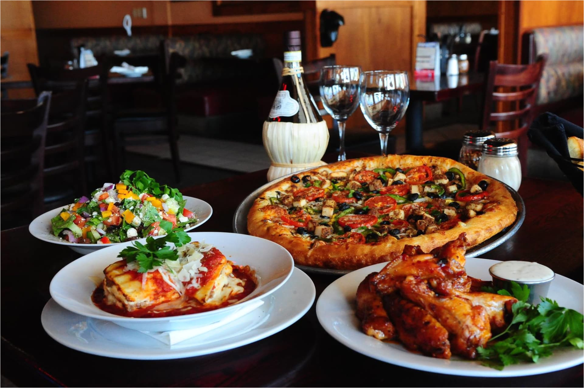 table with pizza lasagna salad and wings