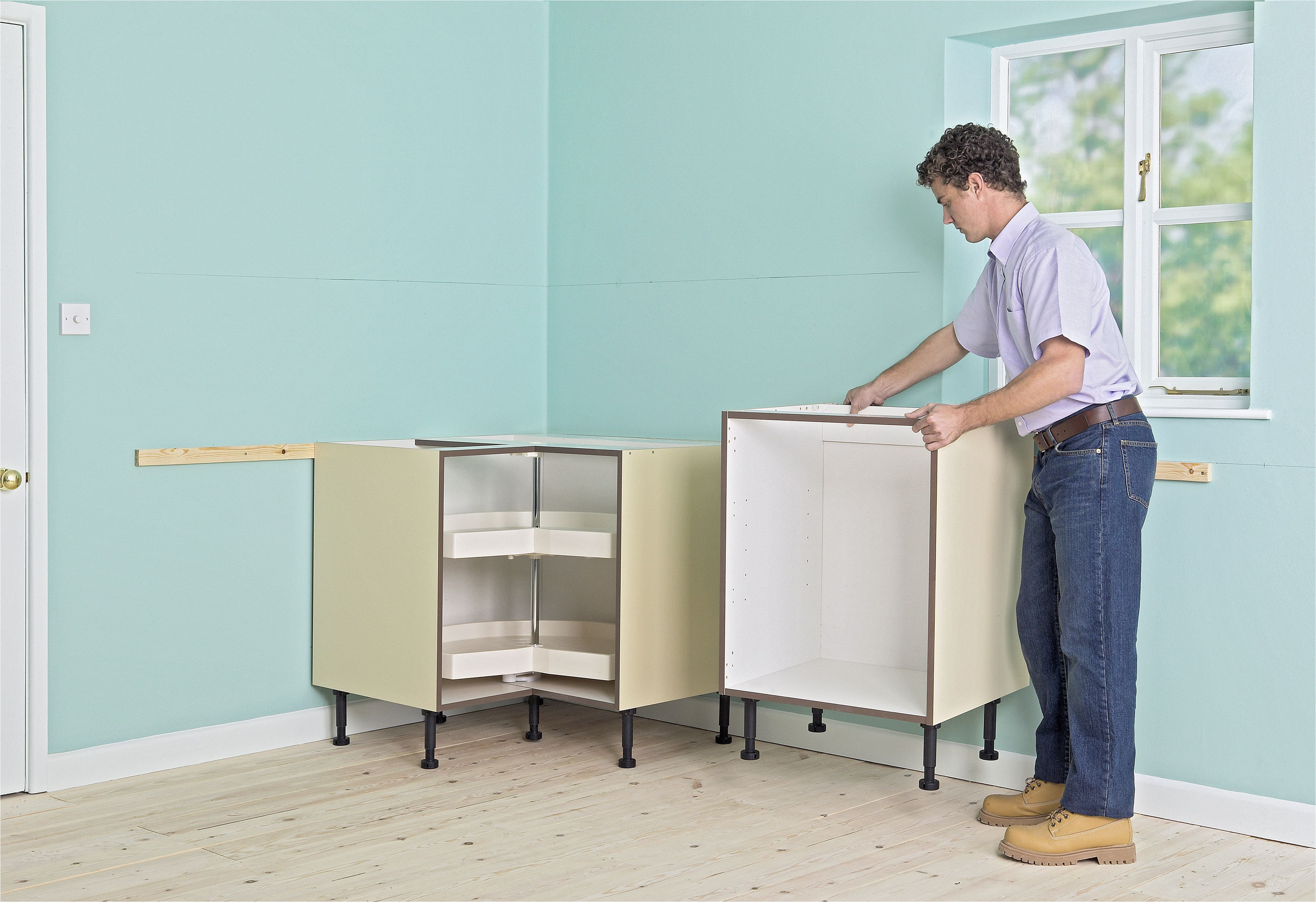 man positioning kitchen units against a corner of a room next to a window 149269213 57f4fe0e5f9b586c352d68c6 jpg