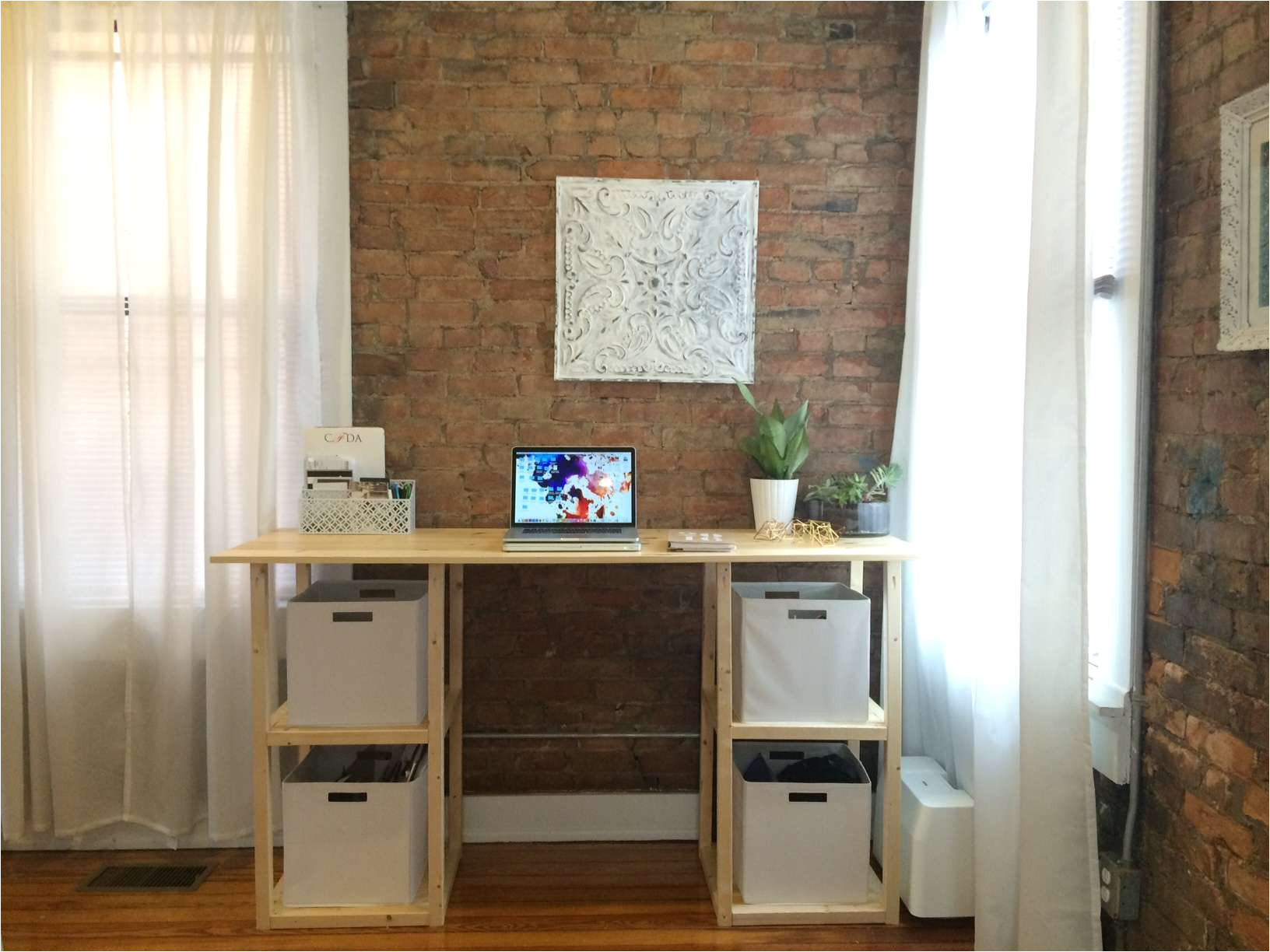 a diy desk by a brick wall and windows