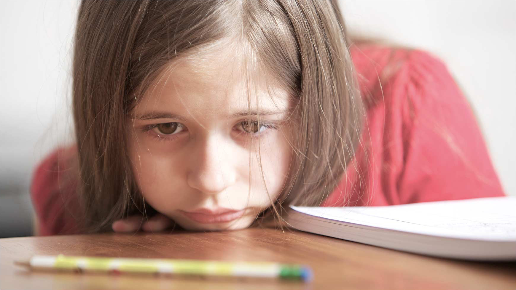 close up of a girl at school with head on her desk looking lonely and