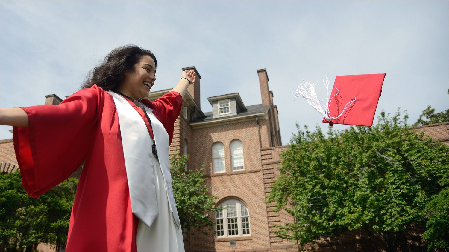 an nc state graduate throws her cap in front of holladay hall