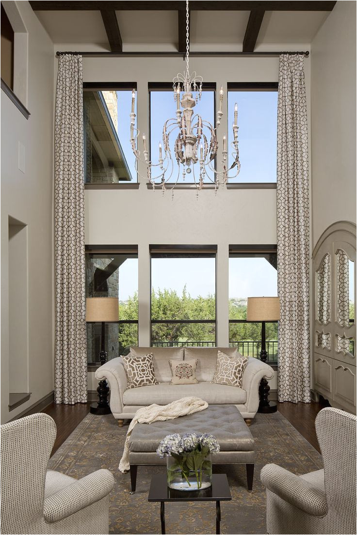 custom two story geometric embroidered draperies frame the living room windows the room is