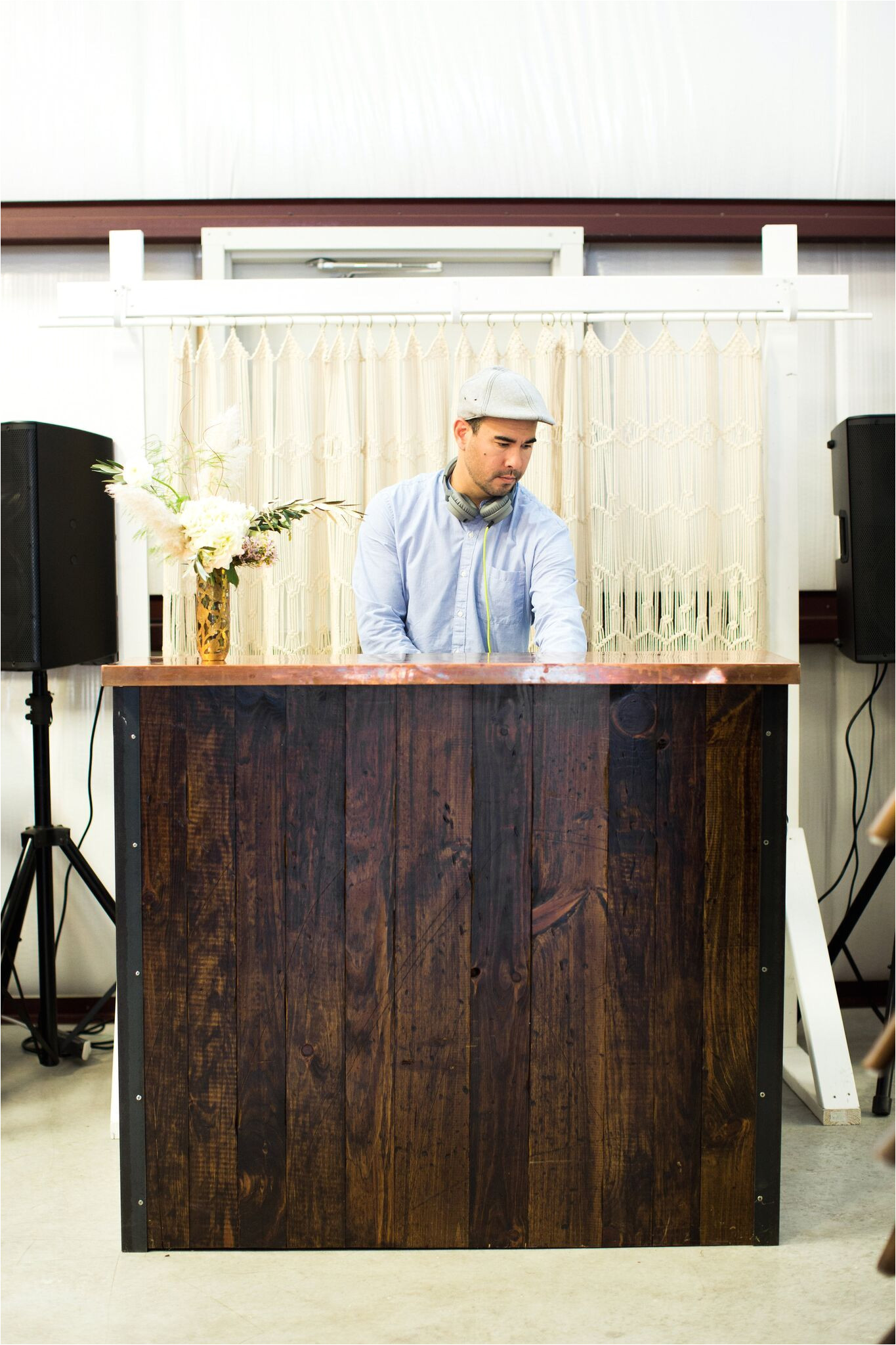 party dj booth using a rustic wood bar with a modern copper top in front of a macrame backdrop via birch brass vintage rentals for weddings and special