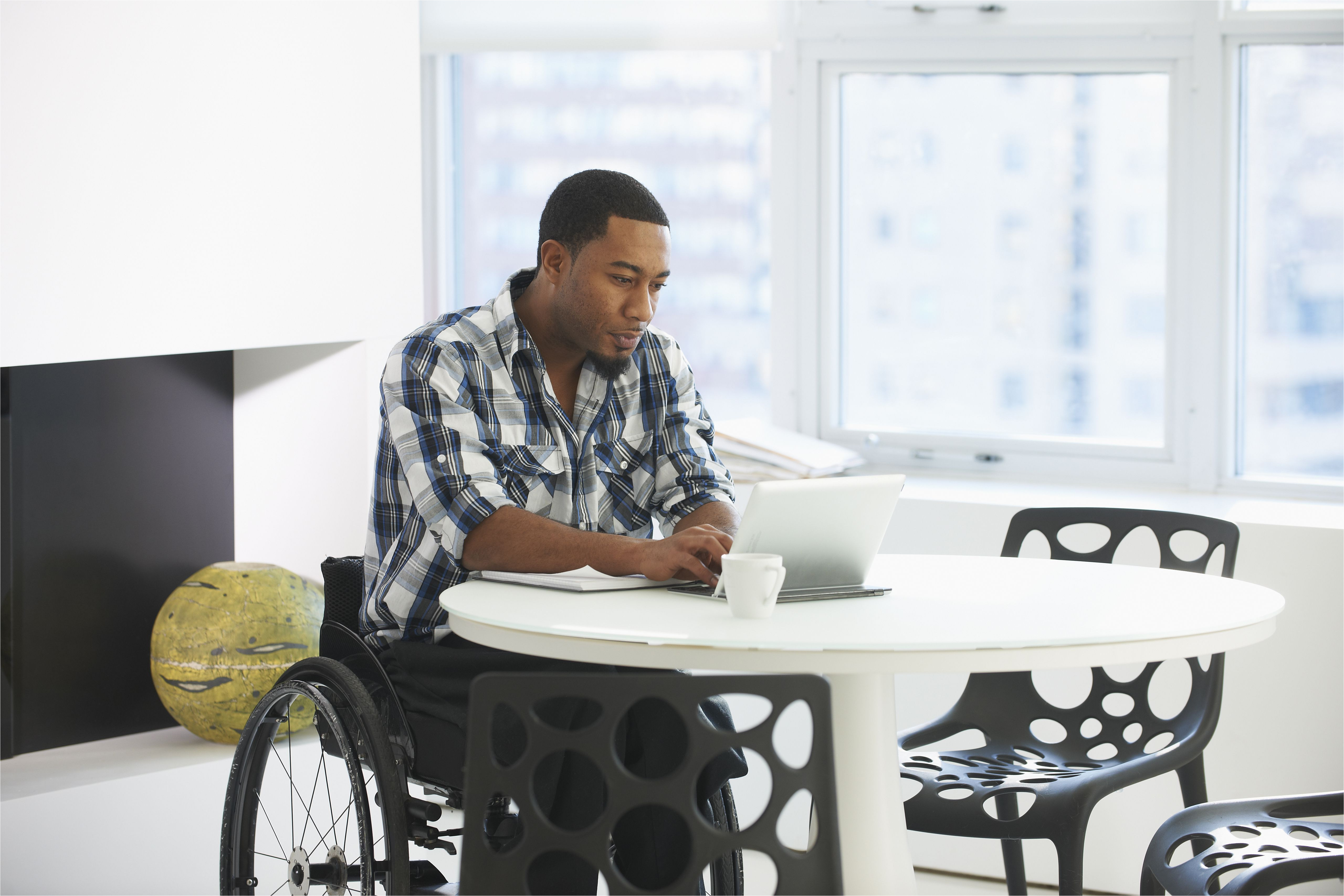black businessman in wheelchair using laptop at table 672161631 5a6b3a3a43a1030037040e7e jpg