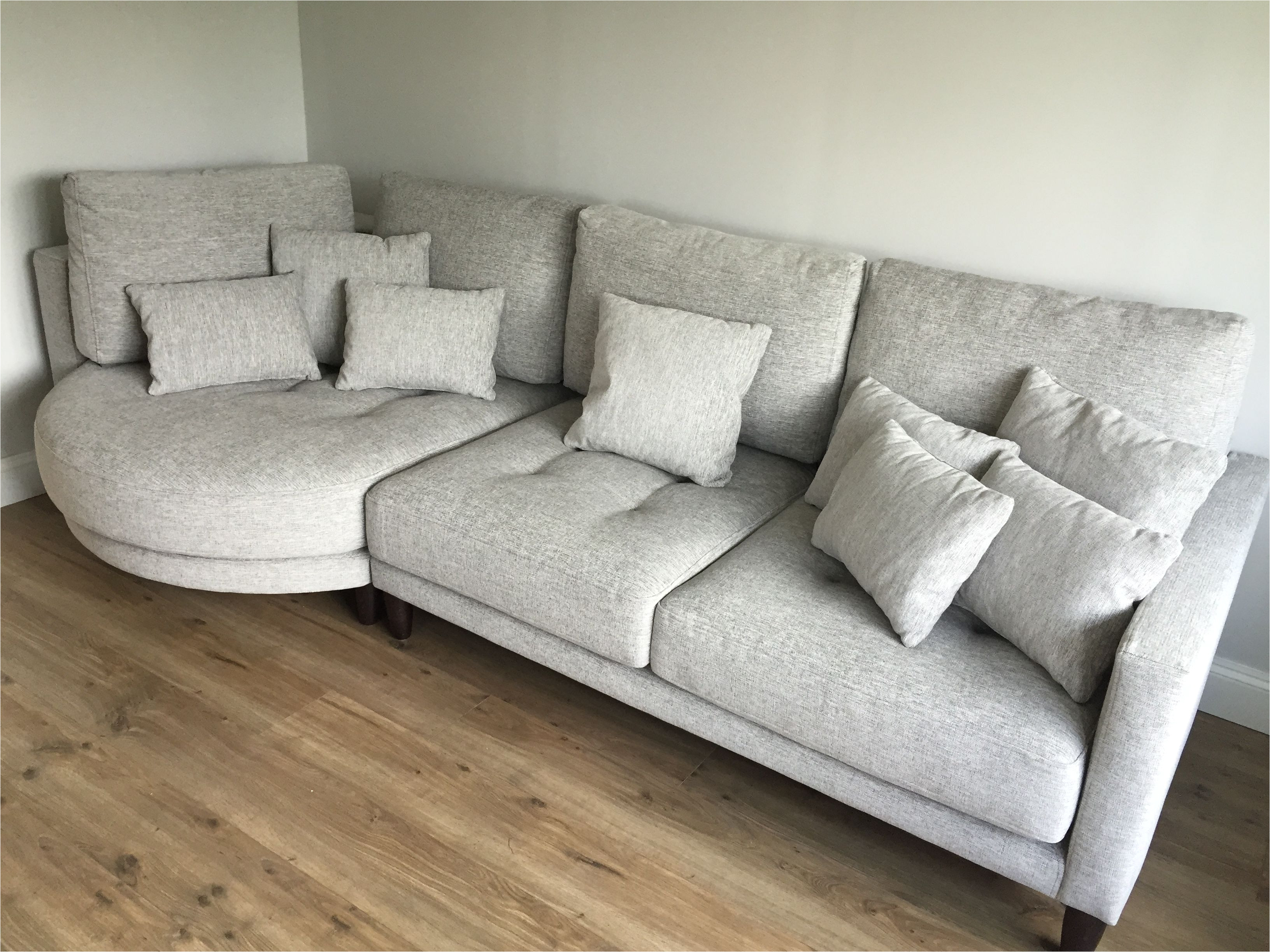 left hand facing rounded chaise with sofa section in light grey fabric and dark wood legs
