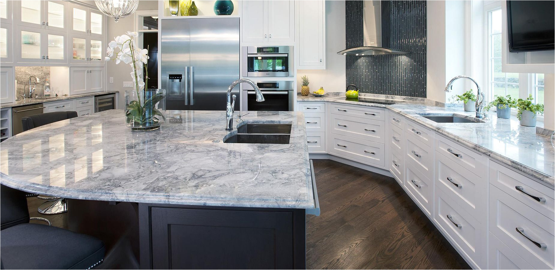 white fantasy countertop with black island and white cabinets and black glass mosaic tile