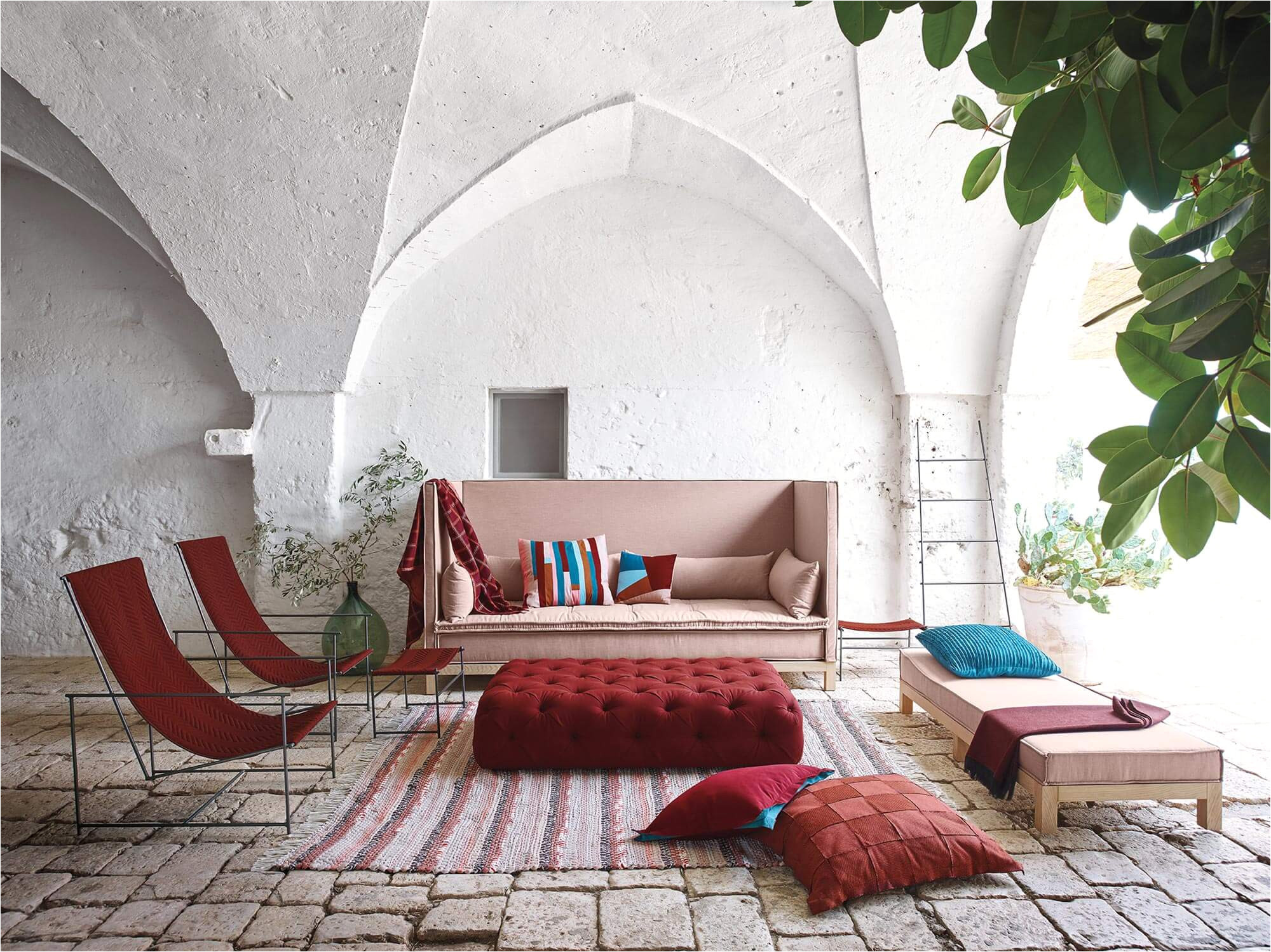 a living room with a large sofa chairs and a tufted ottoman in hues