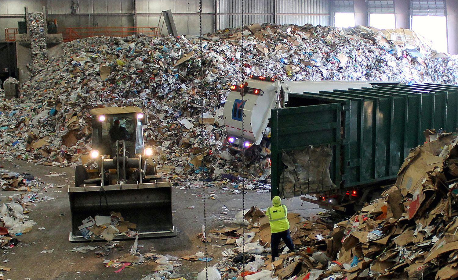 trucks dump their loads of single stream recycling on the tip floor at resource management s materials recovery facility mrf in earth city mo